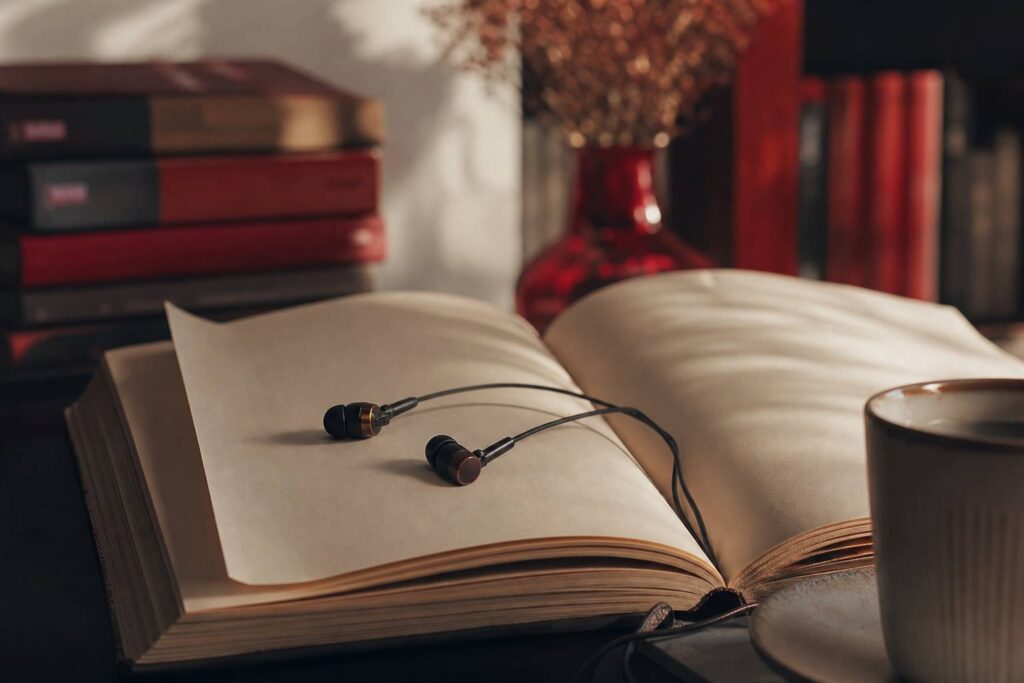 Migliori app per audiolibri: confronto abbonamenti, ereader et livres sur table en bois, ambiance librairie