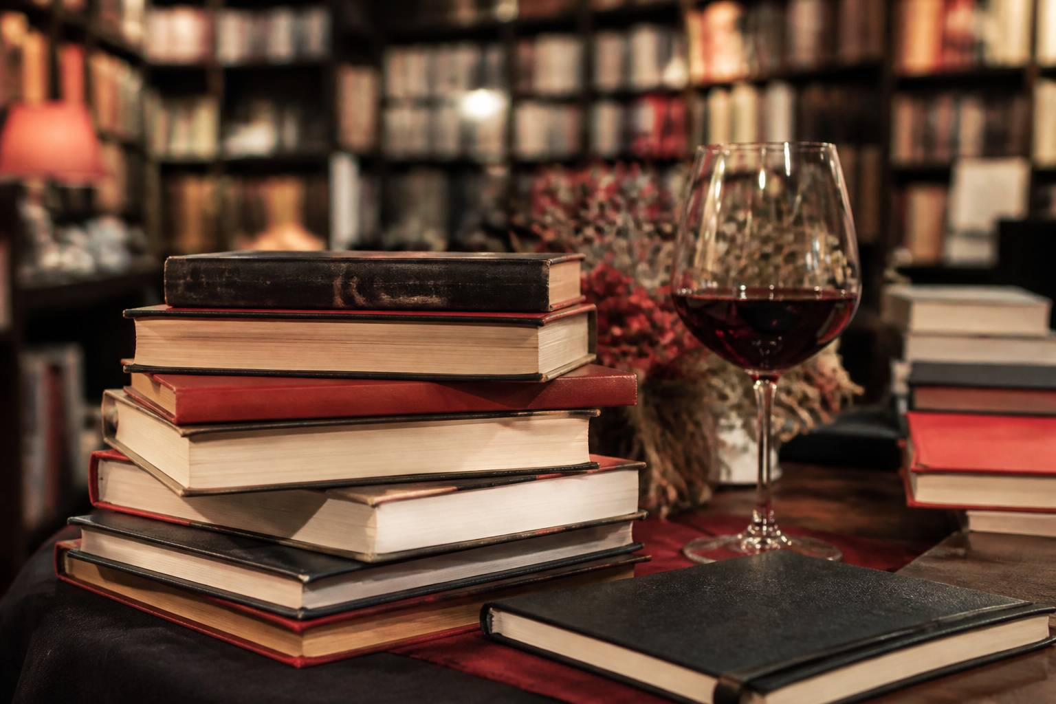 Pile de livres avec un verre de vin rouge sur une table d'exposition