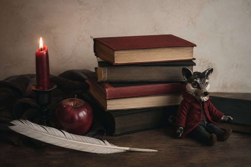 Livres anciens, plume et marionnette de loup sur fond ivoire évoquant les contes